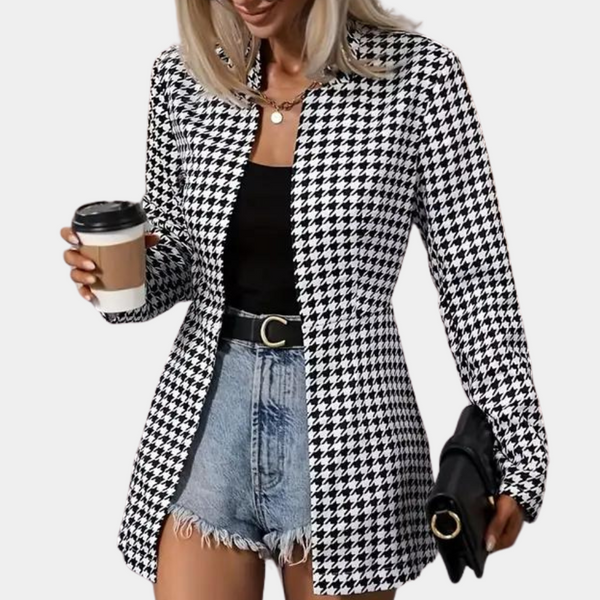 Vrouw in zwart-wit pied-de-poule blazer, zwarte top, denim shorts, met koffie en clutch. Modieuze dameskleding, casual stijl.