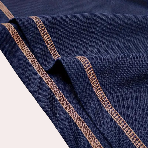 Donkerblauwe stof met beige stiksels, close-up. Hoogwaardige textiel, geschikt voor kleding en interieur. Duurzaam en stijlvol ontwerp.