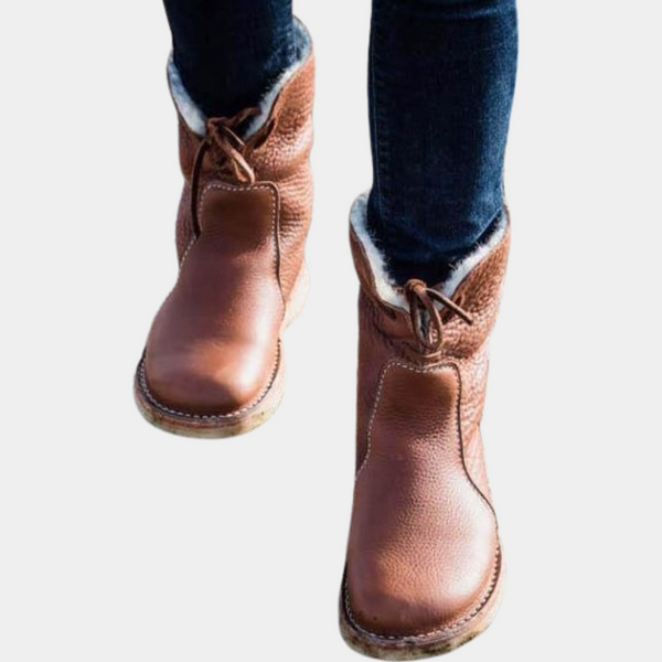 Bruine leren laarzen met veters en schapenvacht voering, gedragen met donkere jeans. Comfortabele winterlaarzen voor dames.