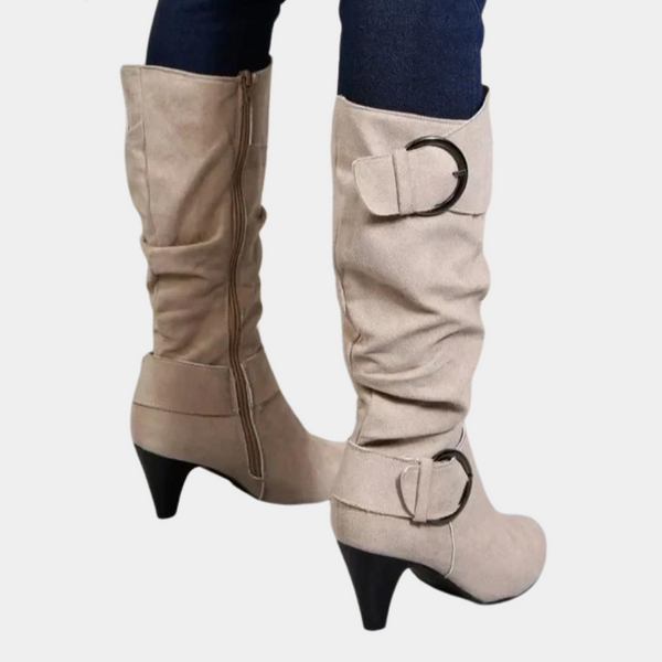 Beige dameslaarzen met hoge hak, suède look, ritssluiting en decoratieve gespen. Trendy knielaarzen voor herfstmode.