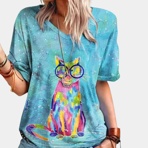 Vrouw draagt blauw T-shirt met kleurrijke katprint en bril, casual mode, trendy dameskleding, artistiek ontwerp, zomeroutfit.