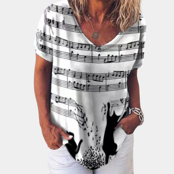 Vrouw draagt wit T-shirt met muzieknoten en silhouetten van katten. Modieuze dameskleding, casual stijl, muziek en dierenprint.