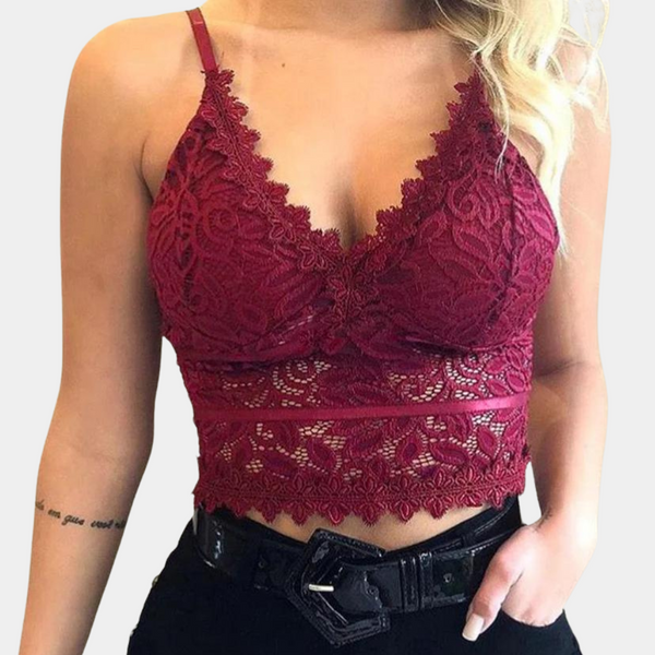 Vrouw in wijnrode kanten crop top met spaghettibandjes, gedetailleerd bloemenpatroon, gecombineerd met zwarte broek en riem. Trendy damesmode.