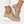 Beige sneakers met sleehak, metallic details en perforaties, gedragen met witte broek. Modieuze damesschoenen, comfortabel en stijlvol.