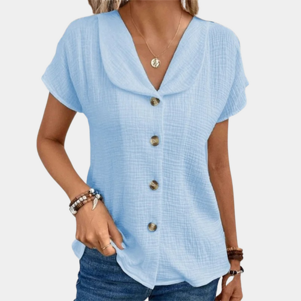 Vrouw draagt lichtblauwe blouse met korte mouwen en knoopsluiting, casual stijl. Perfect voor zomermode, dameskleding, trendy outfit.