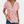 Vrouw draagt roze blouse met knoopsluiting en korte mouwen, gecombineerd met blauwe jeans. Modieuze dameskleding, casual zomeroutfit.