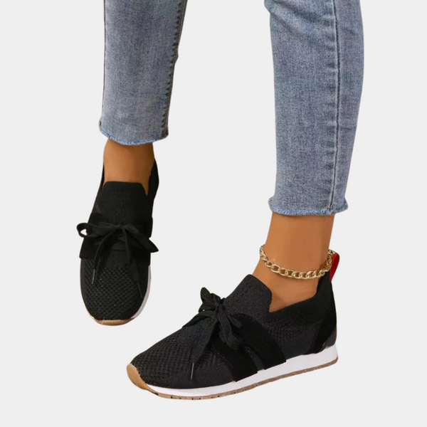 Zwarte dames sneakers met veters, gebreide stof en witte zool, gedragen met blauwe jeans. Comfortabele en modieuze schoenen voor dagelijks gebruik.