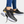 Zwarte sneakers met witte zool en gouden details, gedragen door persoon in blauwe jeans. Stijlvolle sportschoenen voor dagelijks gebruik.