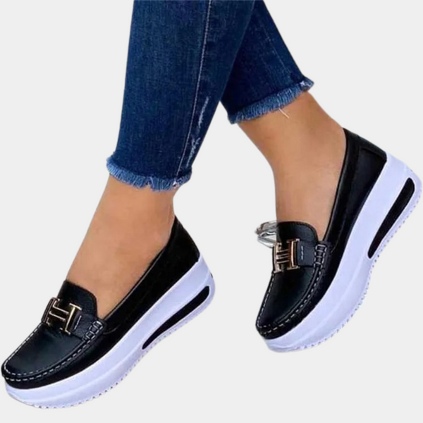 Zwarte loafers met witte plateauzolen en gouden gesp, gedragen met blauwe jeans. Modieuze damesschoenen, comfortabel en trendy design.