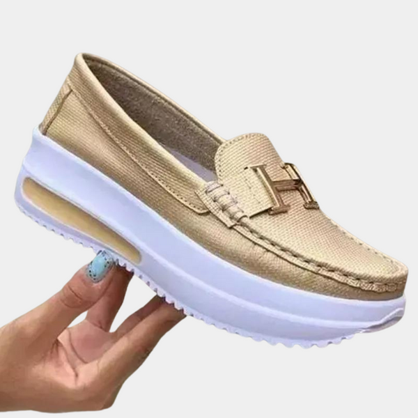 Gouden damesloafer met verhoogde witte zool, H-logo op de wreef, comfortabele instapper, modieuze casual schoen, trendy en stijlvol design.