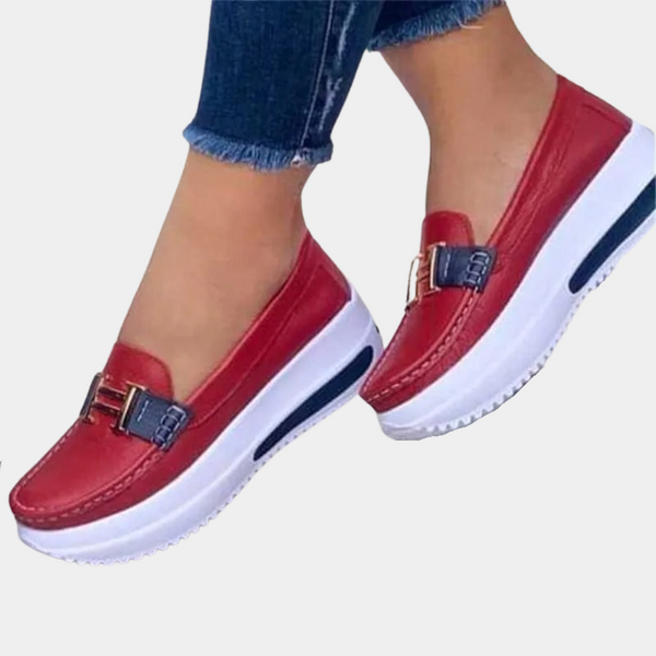 Rode dames loafers met dikke witte plateauzool en gouden gesp, gedragen met blauwe jeans. Comfortabele en modieuze schoenen voor dagelijks gebruik.