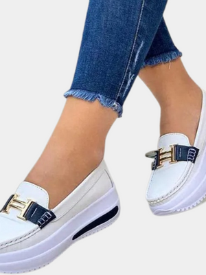 Witte dames loafers met verhoogde zool, gouden gesp en blauwe accenten, gedragen met jeans. Comfortabele en stijlvolle schoenen voor dagelijks gebruik.