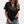 Vrouw draagt zwarte blouse met korte mouwen en knoopsluiting, gecombineerd met denim shorts. Modieuze casual dameskleding, zomeroutfit.