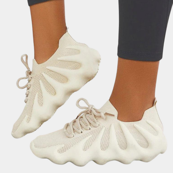 Beige sneakers met uniek golvend zoolontwerp, ademend mesh bovenwerk en vetersluiting. Modieuze en comfortabele schoenen voor dagelijks gebruik.