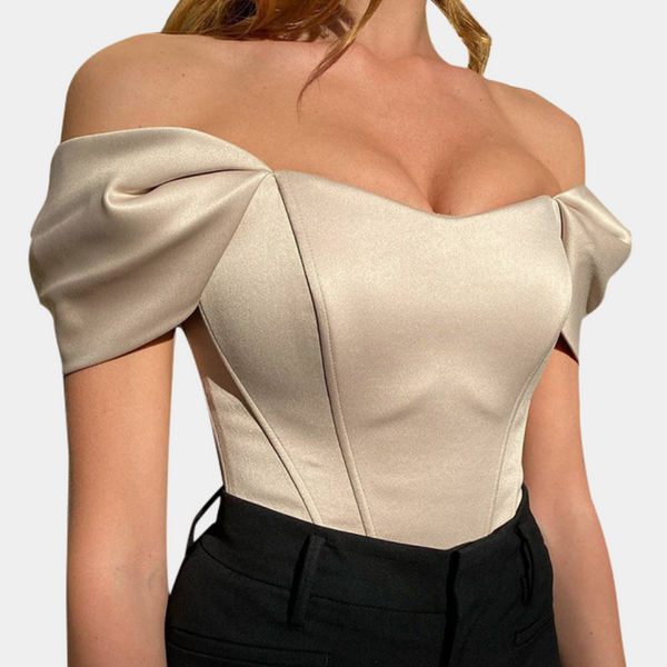Vrouw in elegante off-shoulder top, abrikooskleurig, met pofmouwen en getailleerd ontwerp. Perfect voor avondkleding en modieuze gelegenheden.