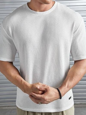 Man in witte, gestructureerde T-shirt met korte mouwen, voor metalen achtergrond. Modieuze herenkleding, casual stijl, comfortabele pasvorm.