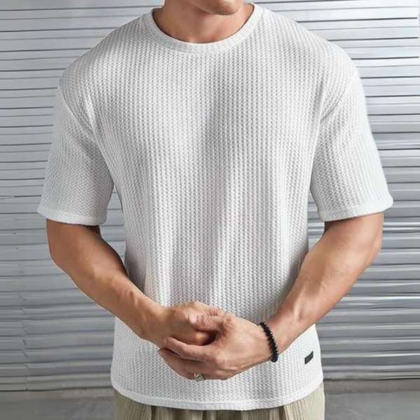 Man in witte, gestructureerde T-shirt met korte mouwen, voor metalen achtergrond. Modieuze herenkleding, casual stijl, comfortabele pasvorm.