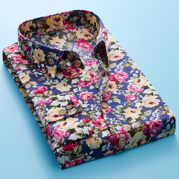 Opgevouwen herenoverhemd met kleurrijke bloemenprint op blauwe achtergrond, ideaal voor modieuze casual outfits. Bloemenoverhemd, herenmode.