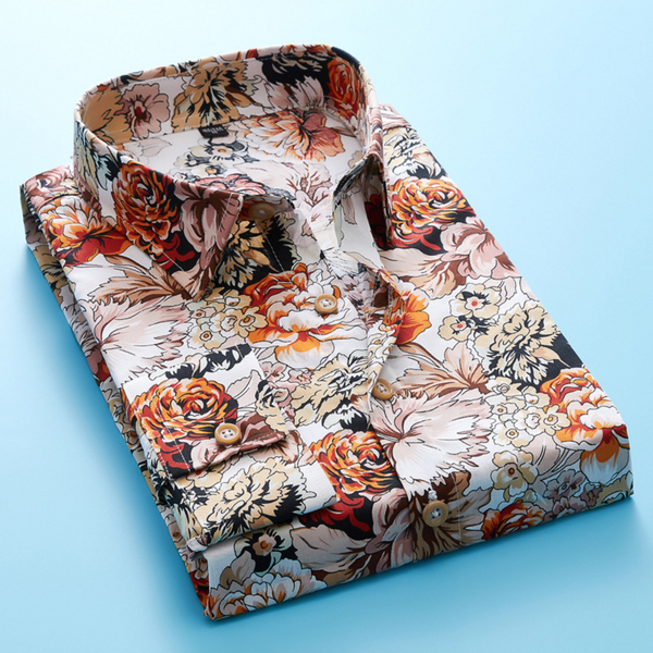 Opgevouwen herenoverhemd met kleurrijke bloemenprint, oranje en beige tinten, op een lichtblauwe achtergrond. Perfect voor modieuze casual outfits.