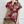 Vrouw draagt een rood-beige blouse met bloemenprint en korte mouwen, gecombineerd met een kaki broek. Modieuze dameskleding, casual stijl.