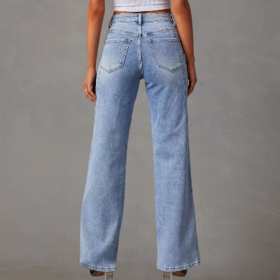 Vrouw in lichtblauwe denim jeans met wijde pijpen, hoge taille en zakken, tegen een grijze achtergrond. Trendy damesmode, casual stijl.