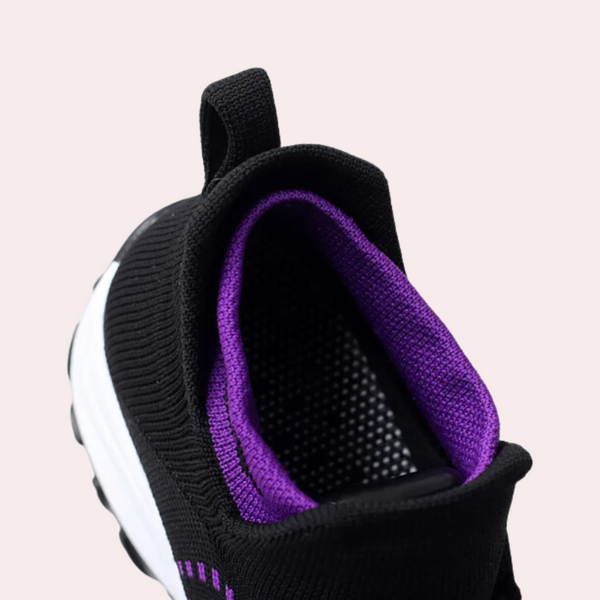 Zwarte sportschoen met paarse voering en witte zool, detail van hiel en lus. Moderne sneaker voor hardlopen en fitness.