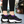 Zwarte en paarse sportschoenen met dikke witte zolen, gedragen door persoon in zwarte broek. Comfortabele sneakers voor dames, ideaal voor hardlopen.