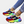 Dames sneakers met regenboogkleuren, blauwe en rode accenten, gele strepen, gedragen met opgerolde jeans en gouden enkelbandjes.