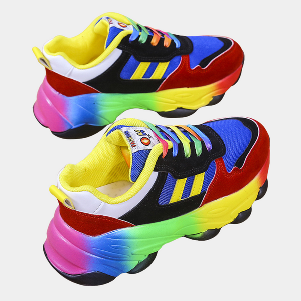 Kleurrijke sneakers met regenboogzool, blauwe en rode accenten, gele binnenkant en meerkleurige veters. Trendy sportschoenen voor modebewuste jongeren.