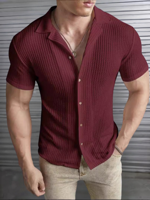 Man in wijnrode gebreide polo met korte mouwen, open kraag en beige broek, voor metalen achtergrond. Stijlvolle herenkleding, casual mode.