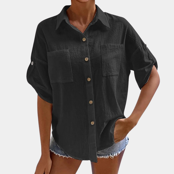 Zwarte damesblouse met korte mouwen, knoopsluiting en borstzakken, gecombineerd met denim shorts. Casual en stijlvolle damesmode.