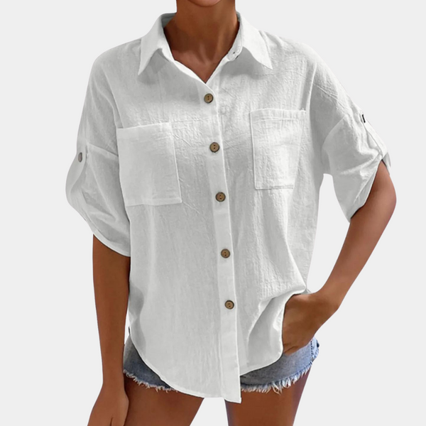 Witte damesblouse met knoopsluiting, opgerolde mouwen en borstzakken, gedragen met denim shorts. Casual en modieuze dameskleding.