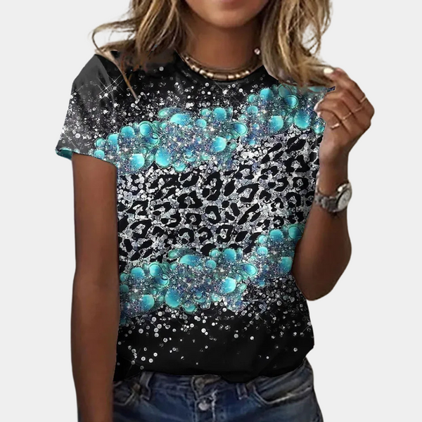Vrouw draagt zwart T-shirt met turquoise en zilveren luipaardprint, casual stijl, korte mouwen, perfect voor modieuze zomerkleding.