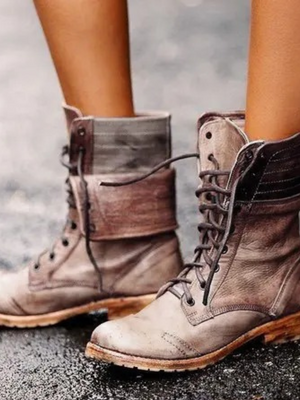 Khaki leren laarzen met veters, gedragen op natte straat. Stijlvolle damesmode, herfst schoenen, robuuste zool, casual outdoor look.