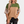 Vrouw in modieuze, geribbelde trui met groene, beige en bruine kleurblokken, gecombineerd met zwarte jeans. Trendy dameskleding, casual stijl.