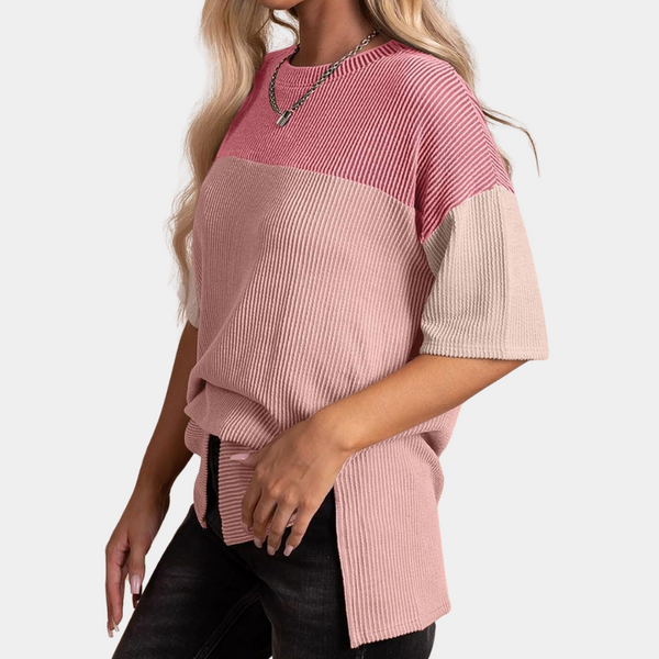 Vrouw draagt roze en perzik kleurige geribbelde trui met korte mouwen, gecombineerd met zwarte jeans. Modieuze dameskleding, casual stijl.