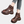 Bruine leren sandalen met dikke zool en perforaties, gedragen door een persoon in jeans. Comfortabele zomerschoenen voor dames, modieus en trendy.