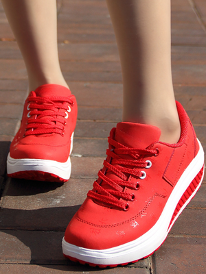 Rode damessneakers met dikke zool, vetersluiting en witte accenten, gedragen op een bakstenen trottoir. Comfortabele en modieuze sportschoenen.