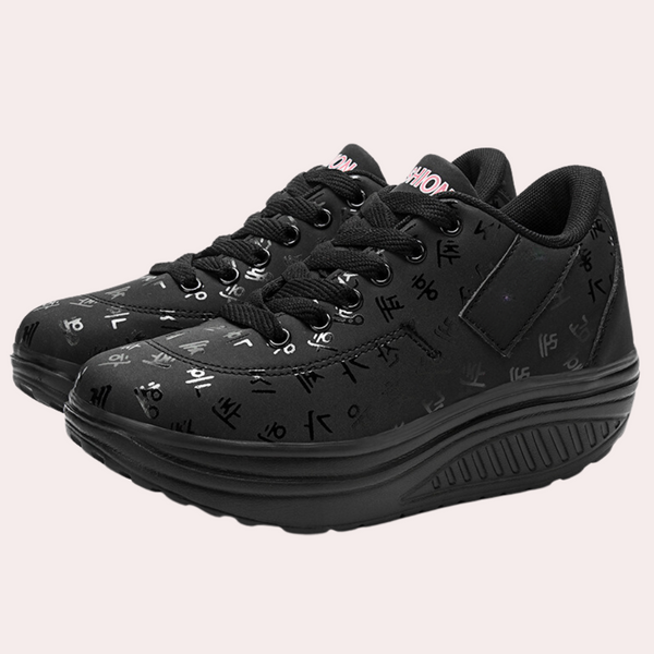 Zwarte damessneakers met verhoogde zool, bedrukt met witte symbolen. Comfortabele, modieuze schoenen voor dagelijks gebruik.