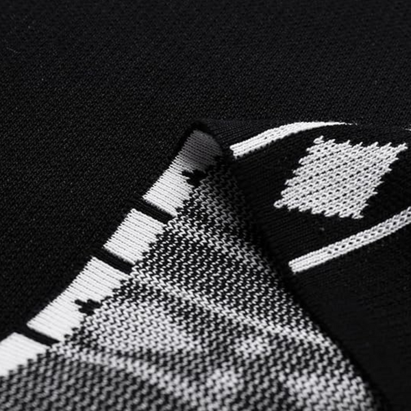 Zwart-wit gebreide stof met geometrisch patroon, close-up. Hoogwaardige textieltextuur, geschikt voor mode en interieurdesign.