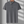 Grijze poloshirt met driehoekpatroon, korte mouwen en knoopsluiting, hangend aan een houten hanger. Perfect voor casual en zakelijke gelegenheden.
