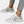 Witte damessneakers met bloemenprint, dikke zool en turquoise enkelbandje, gedragen met grijze jeans. Trendy en comfortabele schoenen.