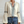 Elegante crèmekleurige blouse met lange mouwen, geplooide stof en blauwe borduursels, gedragen met spijkerbroek. Perfect voor modieuze damesoutfits.