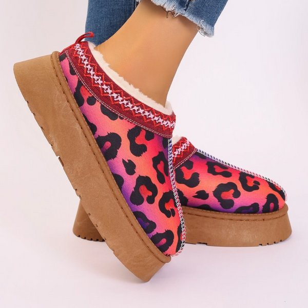 Roze pantoffels met luipaardprint en bruine zool, afgewerkt met rode en witte details. Trendy damesmode, comfortabele warme schoenen.