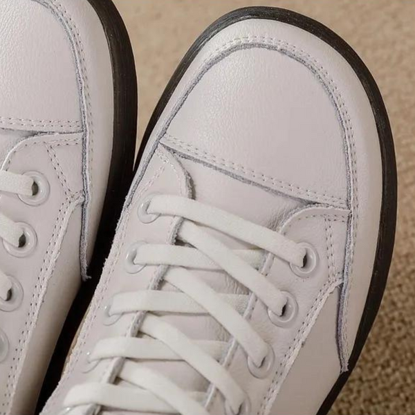 Witte leren sneakers met stiksels en veters, close-up. Modieuze casual schoenen, comfortabele pasvorm, trendy design, hoogwaardige materialen.