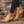 Gouden enkellaarsjes met blokhak, gedragen op grindpad. Stijlvolle damesmode, perfect voor casual en chique outfits. Comfortabele en trendy schoenen.