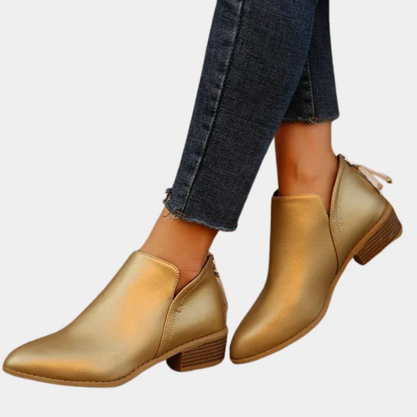 Gouden dameslaarzen met lage hak, gecombineerd met donkere jeans. Stijlvolle enkellaarsjes, perfect voor casual en chique outfits.