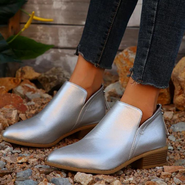 Zilveren enkellaarsjes voor dames, glanzend leer, lage hak, casual stijl, perfect voor herfstmode, gedragen met donkere jeans op grindpad.