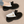 Zwarte damespantoffels met witte voering en strikdetail, comfortabele winterse huisschoenen op beige tapijt. Warme pantoffels voor binnen.
