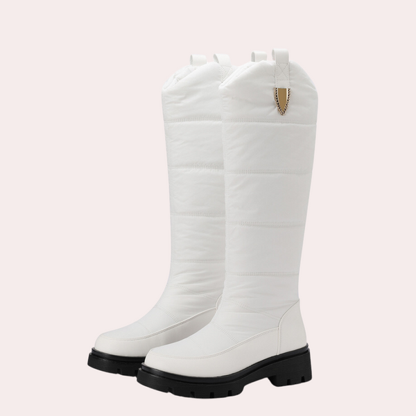 Witte kniehoge laarzen met dikke zwarte zool, gewatteerd ontwerp en gouden detail. Modieuze winterlaarzen voor dames. Trendy en stijlvol schoeisel.